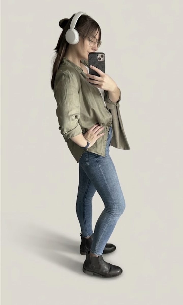 Dominika Škulavíková in an olive shirt and jeans, wearing headphones, taking a mirror selfie
